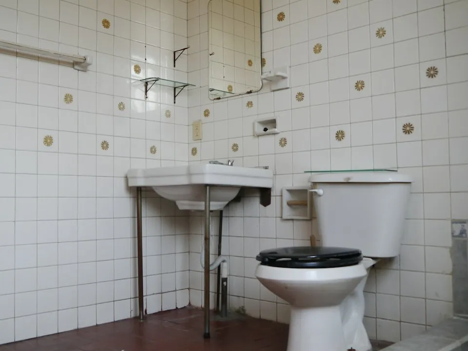 Bathroom before the work: dated tiles, pedestal basin