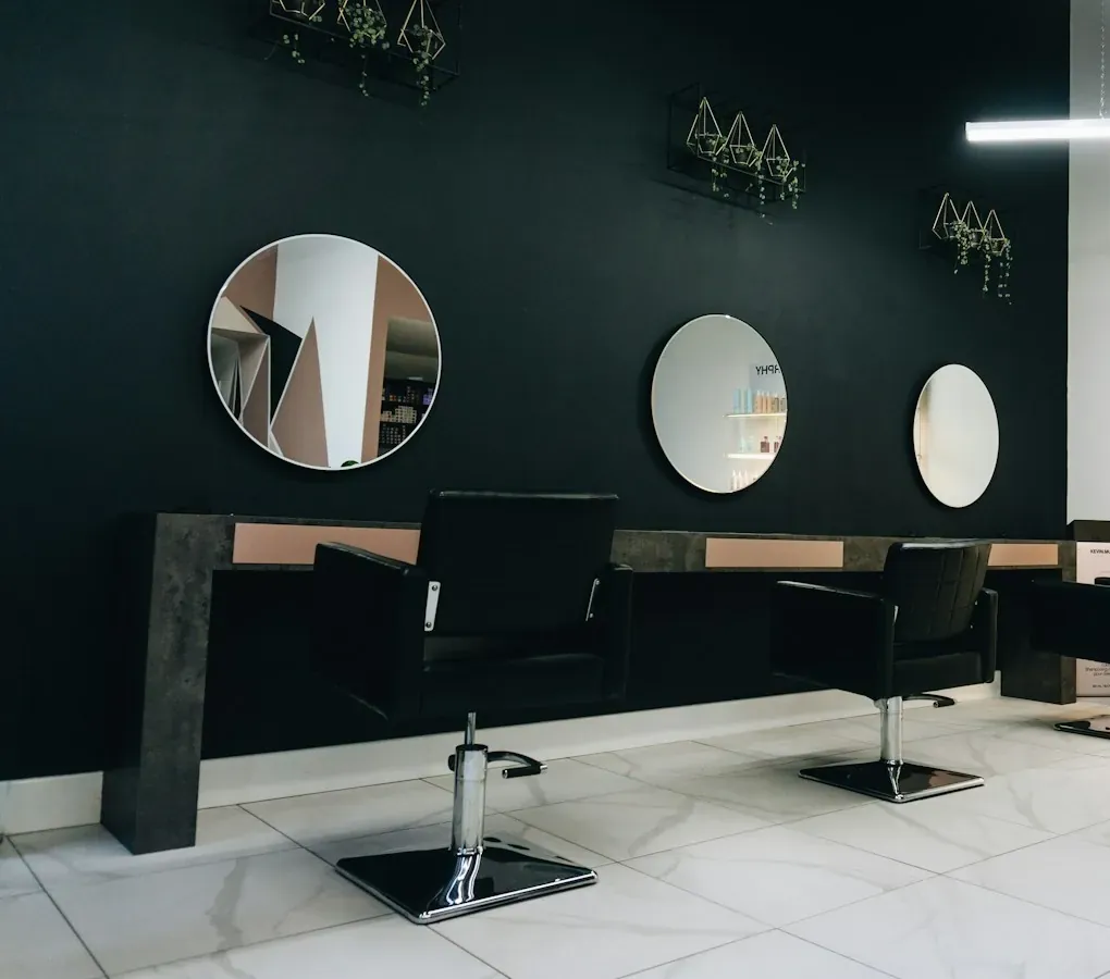 Le salon : fauteuils noirs face à des miroirs ronds