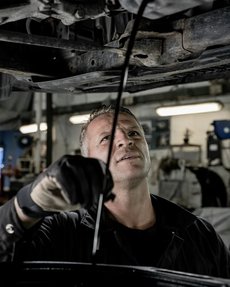 Patrick Delmas sous une voiture, dans l'atelier